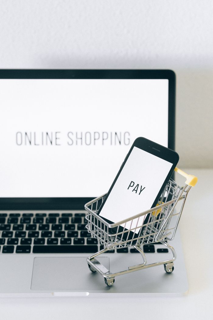 gallery-01 Pametni telefon u minijaturnoj korpi na laptopu simbolizuje online kupovinu i digitalno plaćanje.